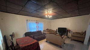 Un salon comprenant un canapé, un téléviseur, une table basse et une nappe à motifs.