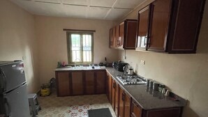 Une cuisine équipée d’un réfrigérateur, d’une cuisinière, d’un évier et de meubles de rangement en bois.