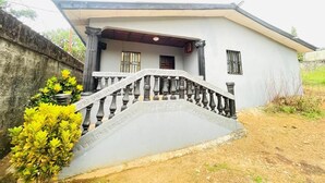 Une maison à deux étages avec un balcon, un escalier et un petit jardin.