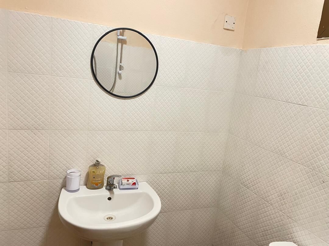 Un baño con lavamanos blanco, un espejo y artículos de aseo en la encimera.