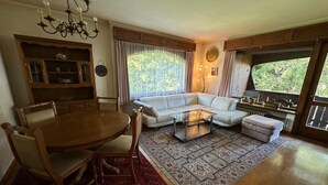 A living room with a dining table, a sofa, a coffee table, and a kitchen area.
