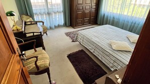 A bedroom with a bed, a desk, a chair, a wardrobe, and a chandelier.