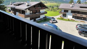 A mountain view from a balcony with a view of a building with a sloped roof and a car parked in front.