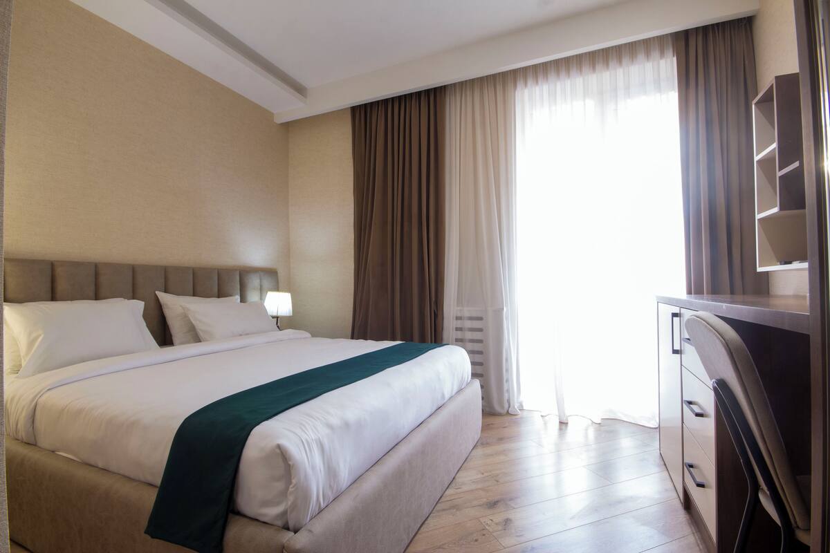 Habitació d'hotel amb un llit gran, un escriptori i una cadira.