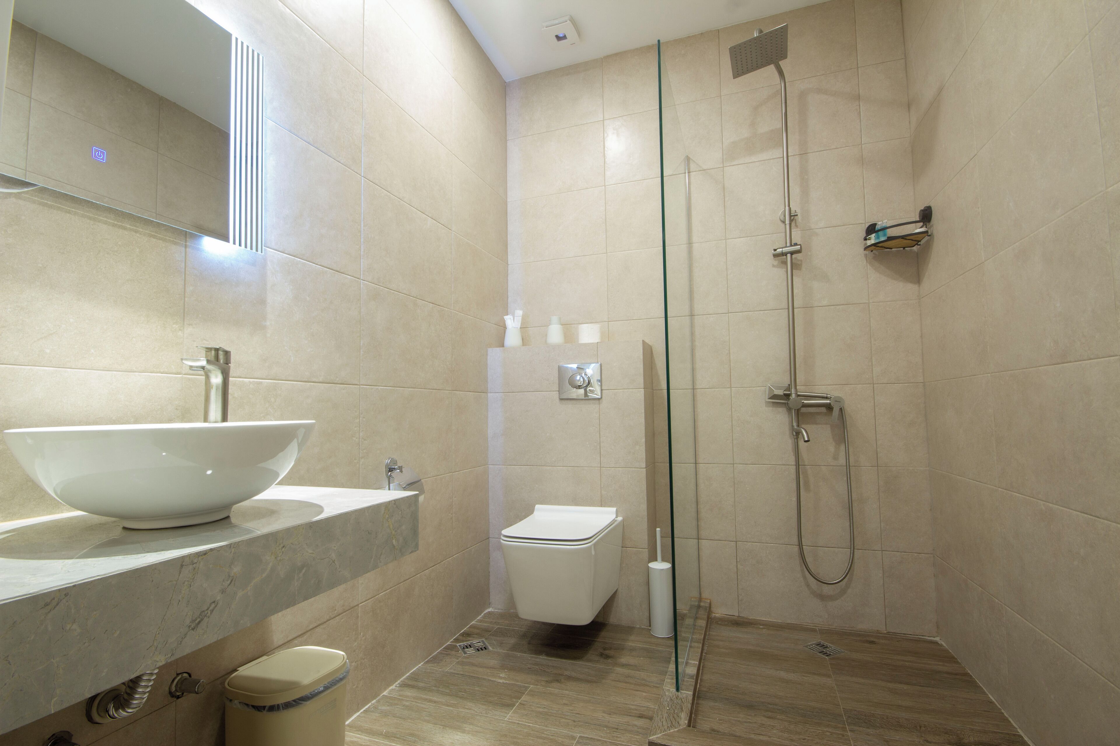 Un baño moderno con un lavamanos grande de color blanco, un inodoro y una zona de ducha con mampara de cristal.