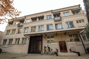 A multi-story building with a large black gate, balconies, and a bicycle parked in front. - Kinor David Glatt Kosher Hotel  (Tbilisi)