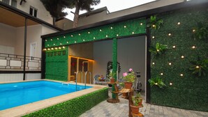A swimming pool with a green wall and potted plants. - Kinor David Glatt Kosher Hotel  (Tbilisi)