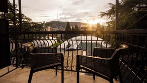 Ein Balkon mit zwei Stühlen und Blick auf eine Stadtlandschaft im Abendrot.