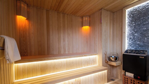 A wooden sauna with benches and a stone wall. - Kinor David Glatt Kosher Hotel  (Tbilisi)