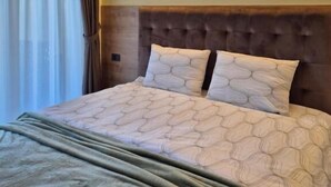 Una habitación de hotel con una cama grande, un cabecero de madera y una ventana con cortinas.