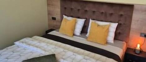 Un dormitorio con una cama grande, cabecera de madera y una mesita de noche con lámpara.