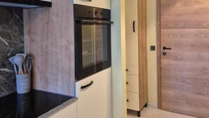 Una cocina compacta con armarios blancos, una encimera negra y un horno empotrado.