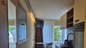 Una cocina compacta con comedor, un televisor en la pared y vistas al exterior a través de la ventana.