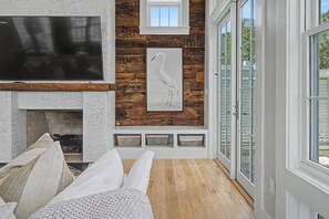 Ein Wohnzimmer mit Kamin, einem Wand-Fernseher und einem großen Fenster mit Blick.