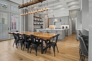 Une cuisine moderne avec une table à manger en bois, des chaises noires et des luminaires suspendus.