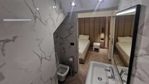 A modern bathroom with marble walls, a large mirror, a sink, and two beds with wooden headboards. - Tirana Room Rentals • Single Bed • Free Wi-Fi • Private Bathroom • TV (Tirana)