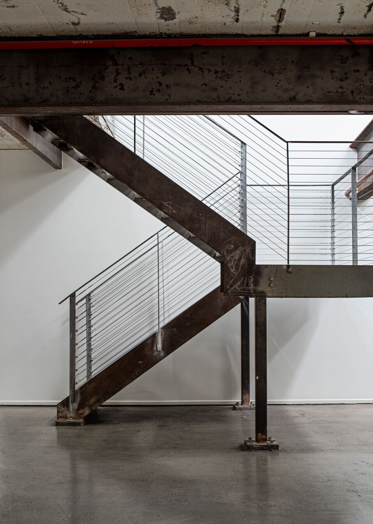 Striking industrial staircase with exposed steel beams and cable balustrades, reflecting the building’s authentic warehouse character