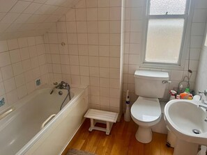 Une salle de bain avec une baignoire, des toilettes et deux lavabos.