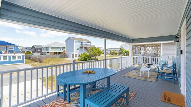 A covered porch with a blue table and benches, a small table, and a chair. - New Listing, Flex Stays, Dog Friendly, Close to Beach and Pier, KD0105 (Kill Devil Hills)