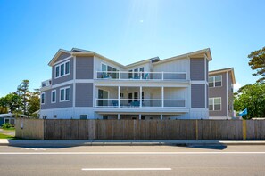 Un immeuble résidentiel de deux étages, doté d’un balcon à l’étage supérieur, d’une clôture en bois à l’avant et surplombant un ciel dégagé.