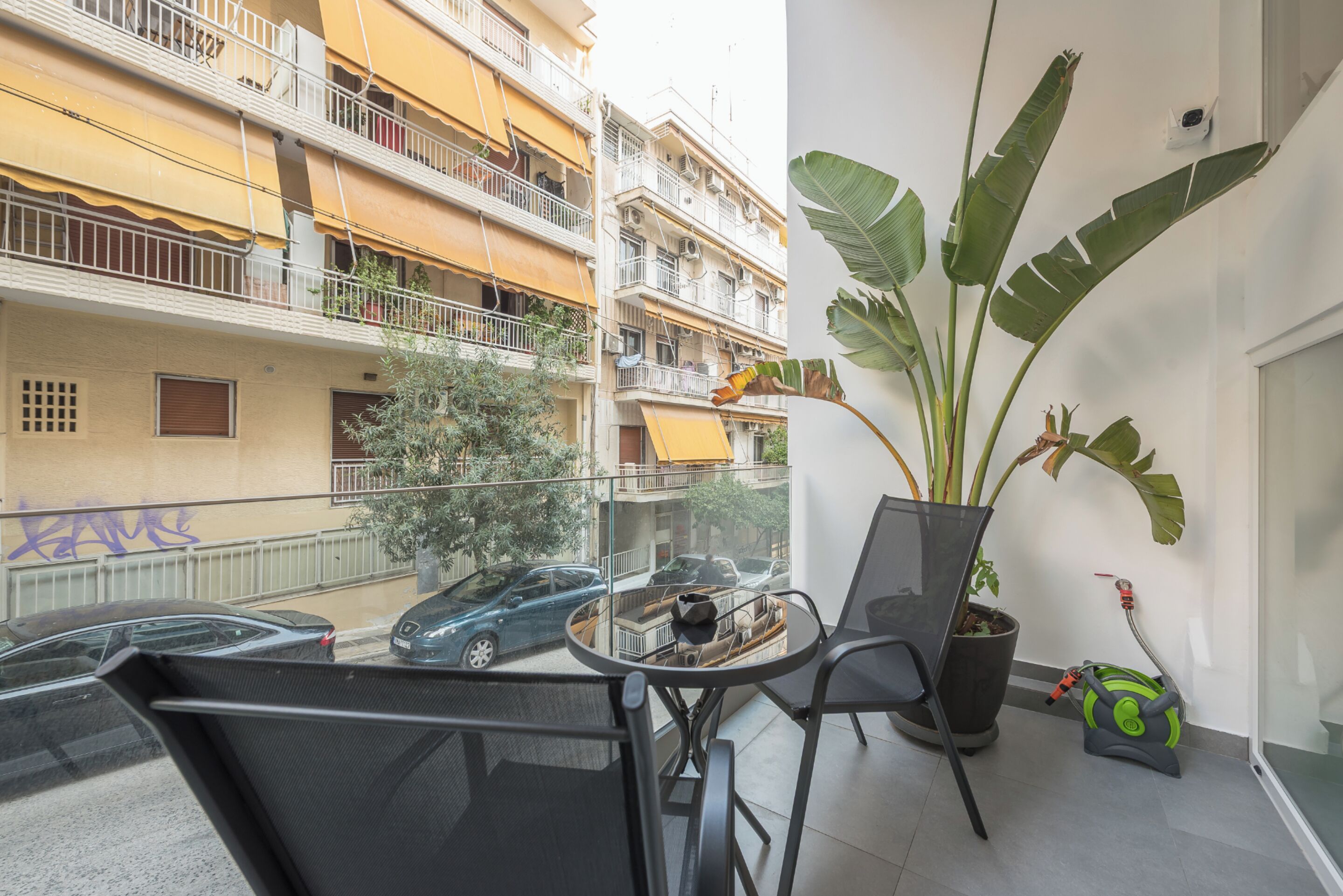 Un balcón con una mesa, sillas, una planta en maceta y una bomba de agua.