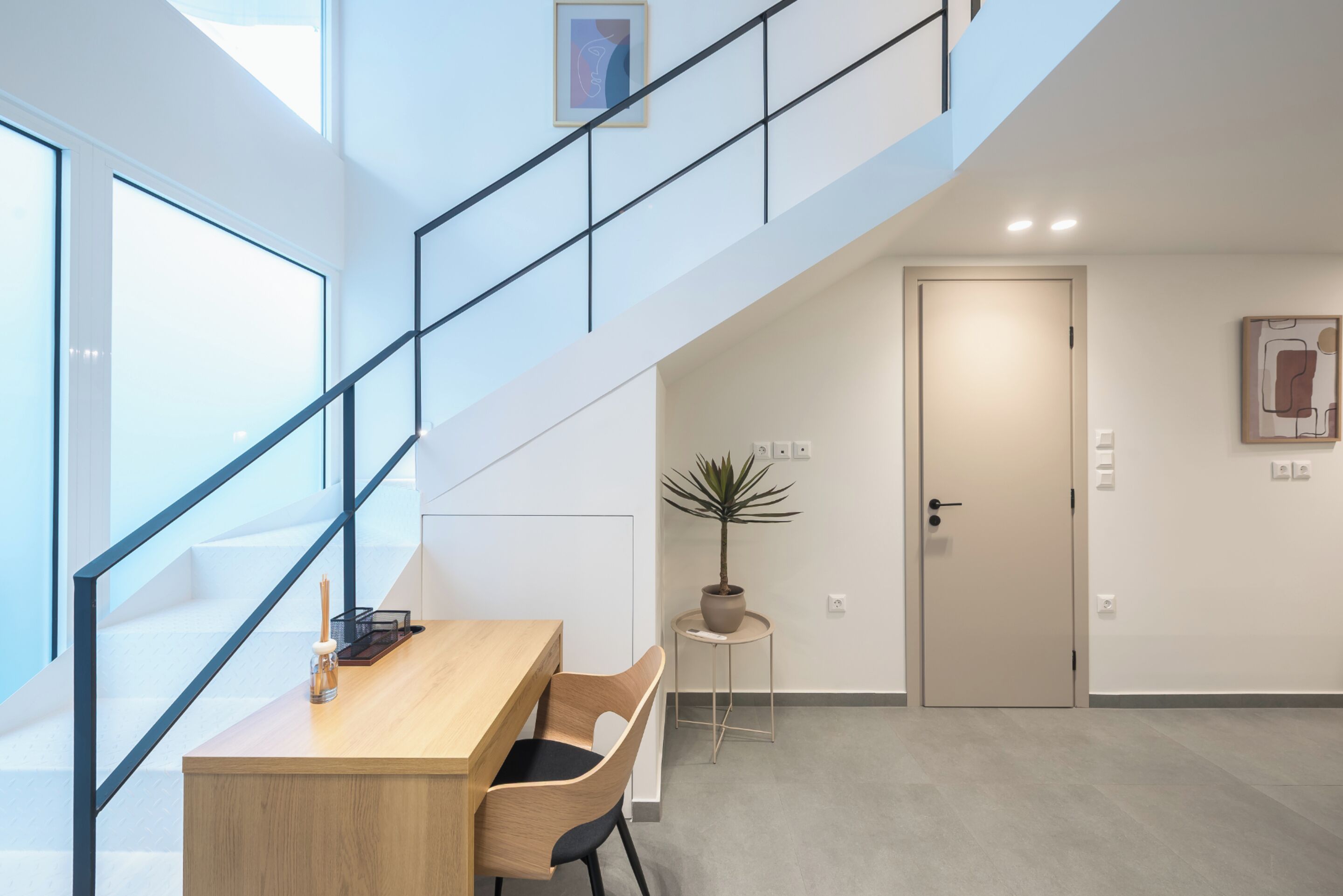 A modern interior with a staircase, a desk, and a potted plant.