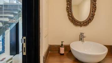 A bathroom with a white sink, a decorative mirror, and a bottle of lotion on the counter.