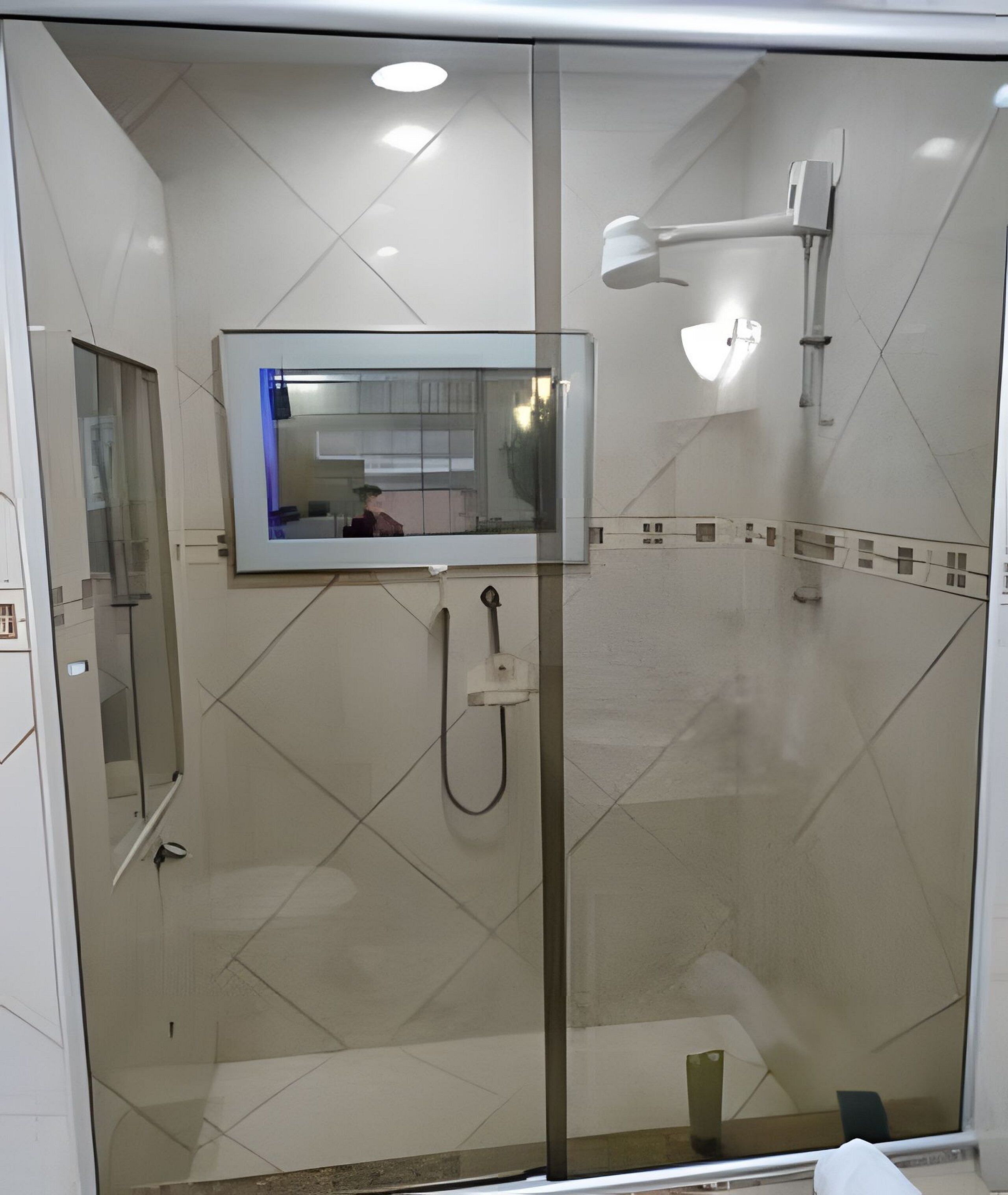 Ein modernes Badezimmer mit Duschkabine aus Glas, einem wandmontierten Spiegel und einer Handbrause.