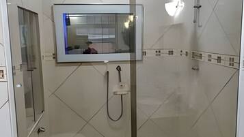 Ein modernes Badezimmer mit Duschkabine aus Glas, einem wandmontierten Spiegel und einer Handbrause.