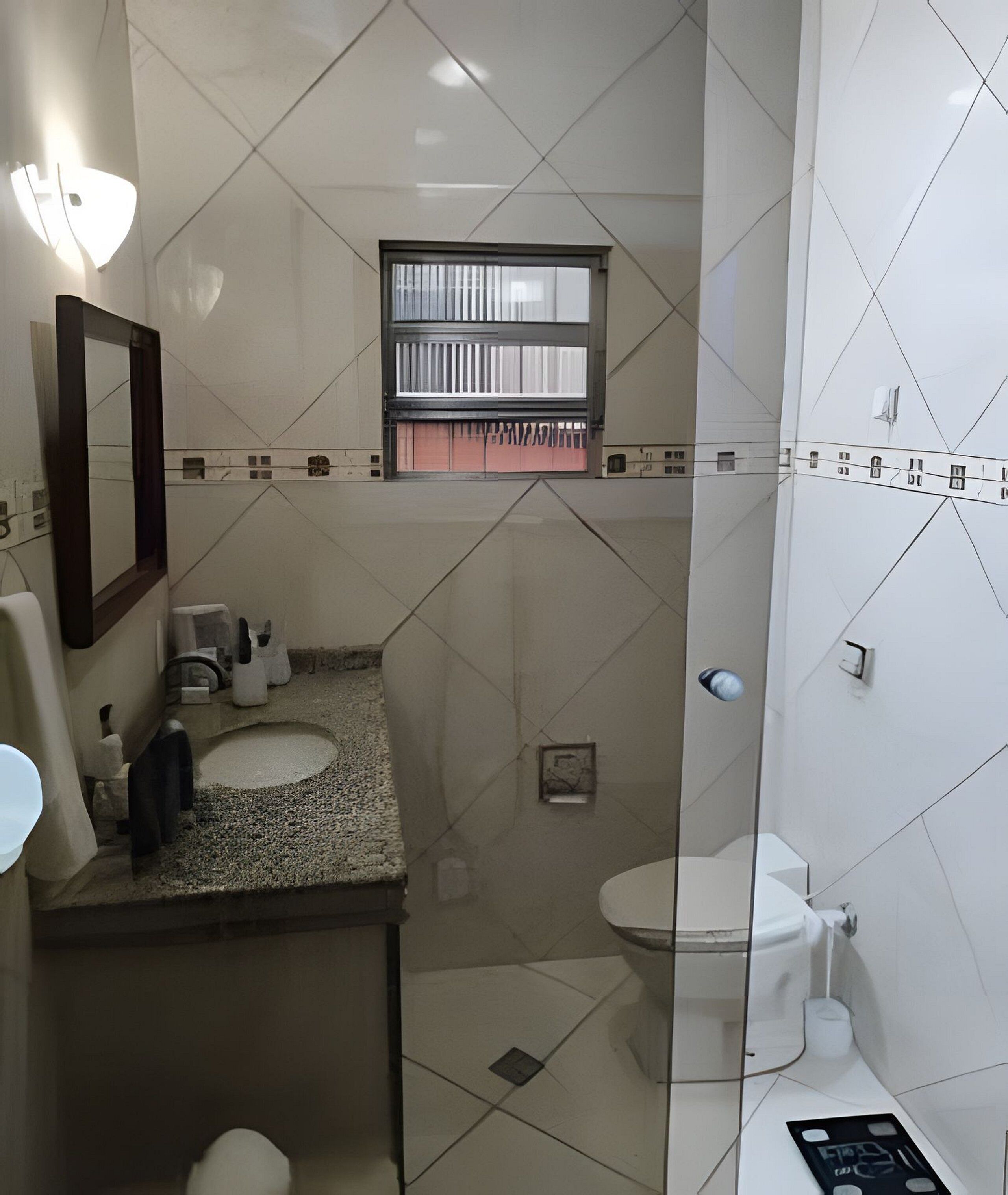 A bathroom with a sink, toilet, and a window above the toilet.