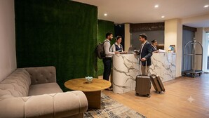 A hotel lobby with a reception desk, a green wall, a sofa, and a coffee table. - Ambika Resort (Rishikesh)
