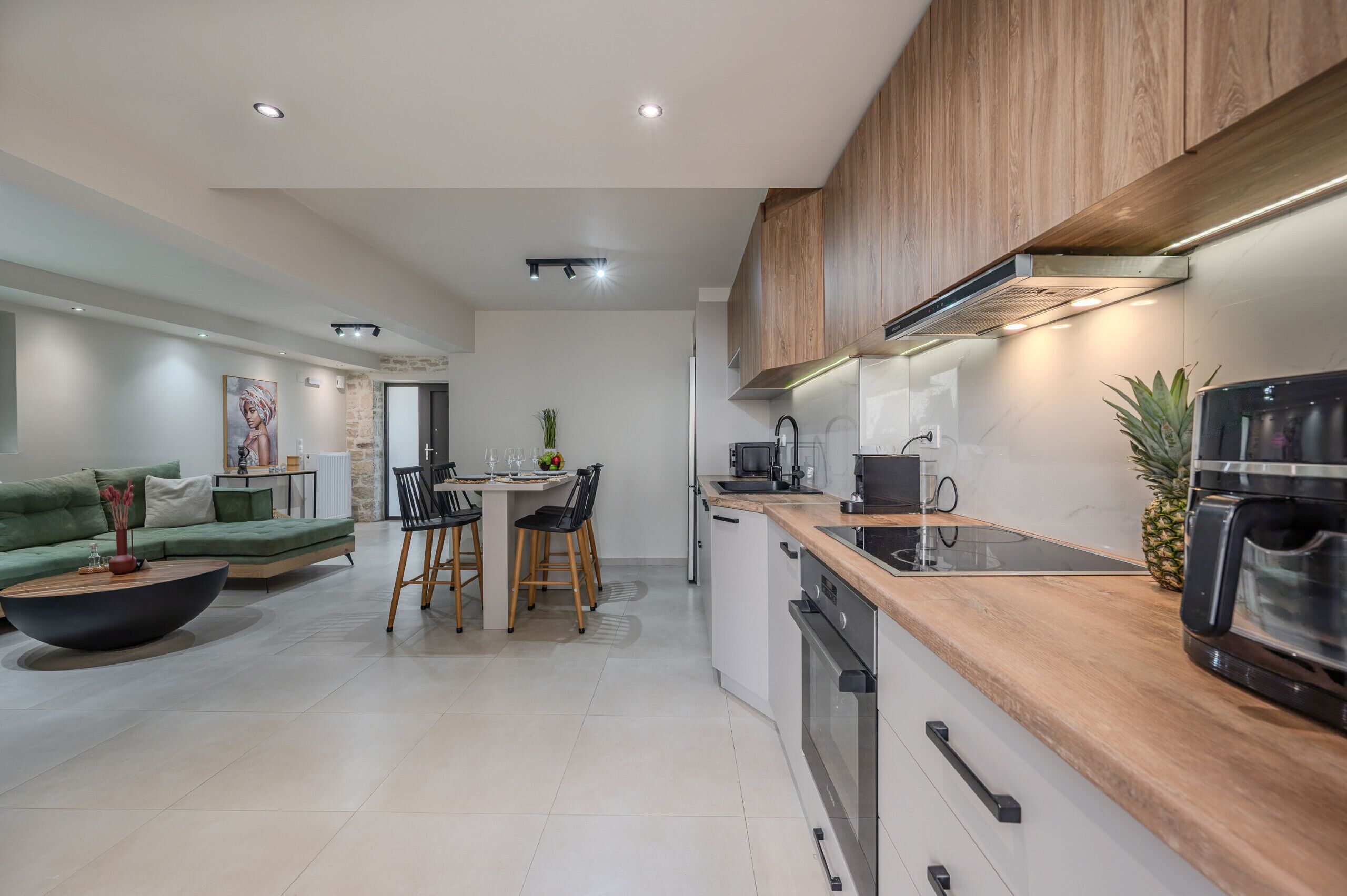 A modern kitchen with wooden cabinets, a built-in oven, and a coffee machine.