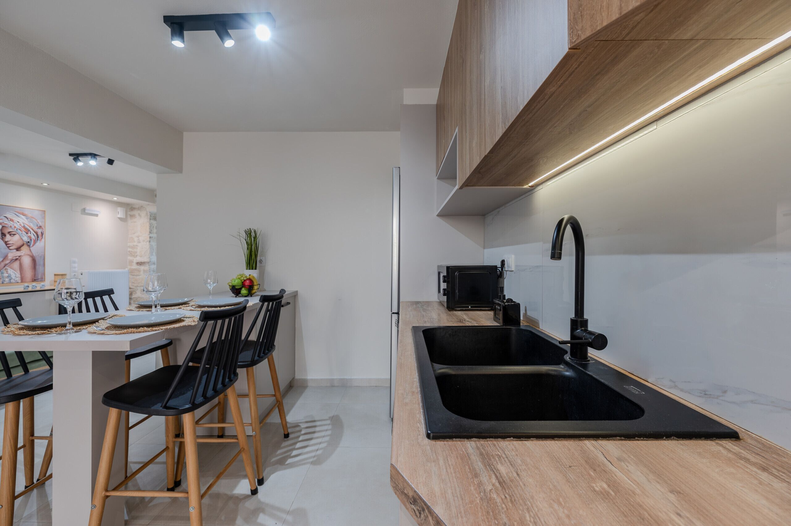 A modern kitchen with a black sink, wooden cabinets, and a dining area with a table set for two.