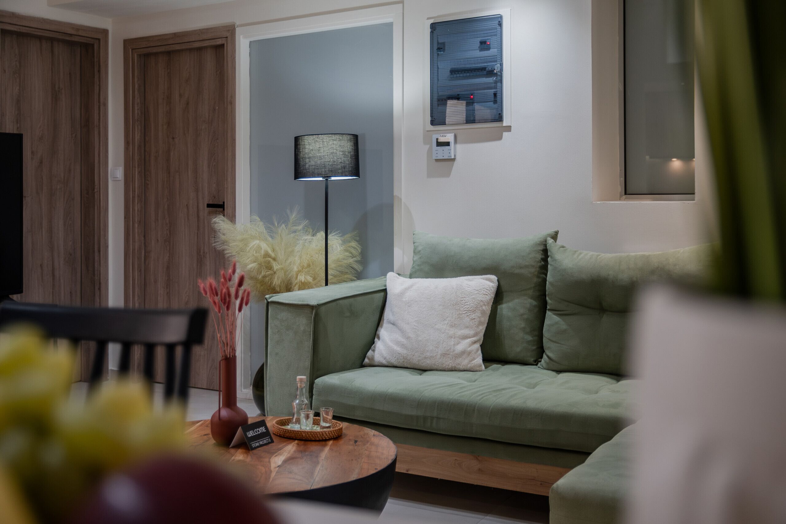 A modern living room with a green sofa, a wooden coffee table, and a floor lamp.