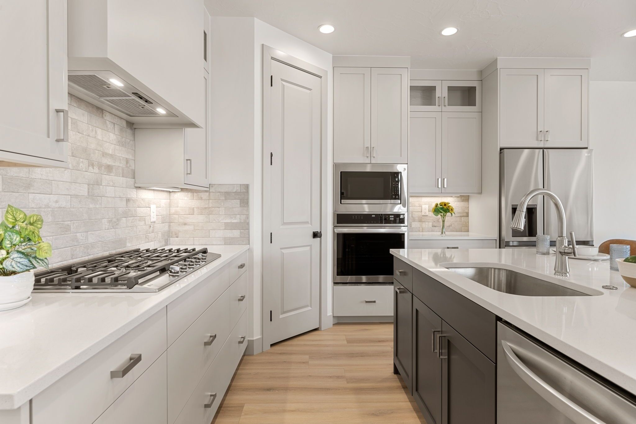 Una cocina moderna con armarios blancos, estufa de acero inoxidable, horno, microondas y refrigerador.