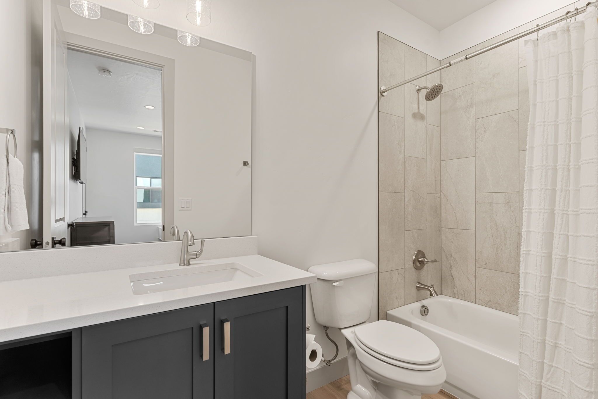 Un bagno moderno con un lavandino bianco, mobili scuri, un water e una cabina doccia in vetro.