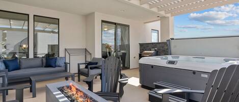 Un patio exterior moderno con una chimenea, zona de estar y un jacuzzi.