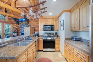 A kitchen with granite countertops, wooden cabinets, a stainless steel sink, a microwave, a stove, and a toaster. - Summit Cabin 3 Bedroom Home (Telluride)