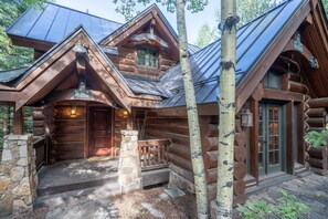 A log cabin with a stone foundation, a wooden porch, and a metal roof. - Summit Cabin 3 Bedroom Home (Telluride)