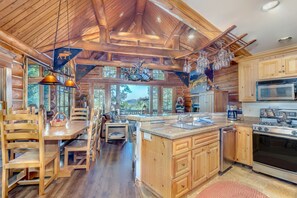 A spacious kitchen with wooden cabinets, a large island, and a dining area with wooden chairs and a table. - Summit Cabin 3 Bedroom Home (Telluride)