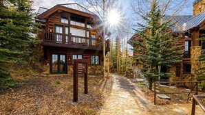 A log cabin-style building with a stone foundation, a wooden deck, and a stone pathway leading to the entrance. - Summit Cabin 3 Bedroom Home (Telluride)