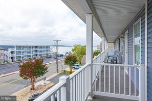 A coastal hotel with a covered porch, a view of the road, and a body of water in the background. - Bayview 4 bedroom - 2 car garage! Discounted June rates! (Ocean City)