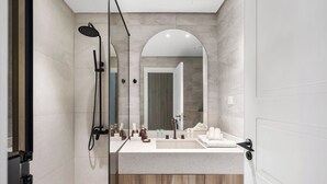 Ein modernes Badezimmer mit Dusche, großem Spiegel und Waschtisch mit Spüle und Handtuchhalter.