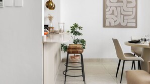 Eine moderne Küche mit Barhocker, einem Esstisch mit Stühlen und einer Pendelleuchte.