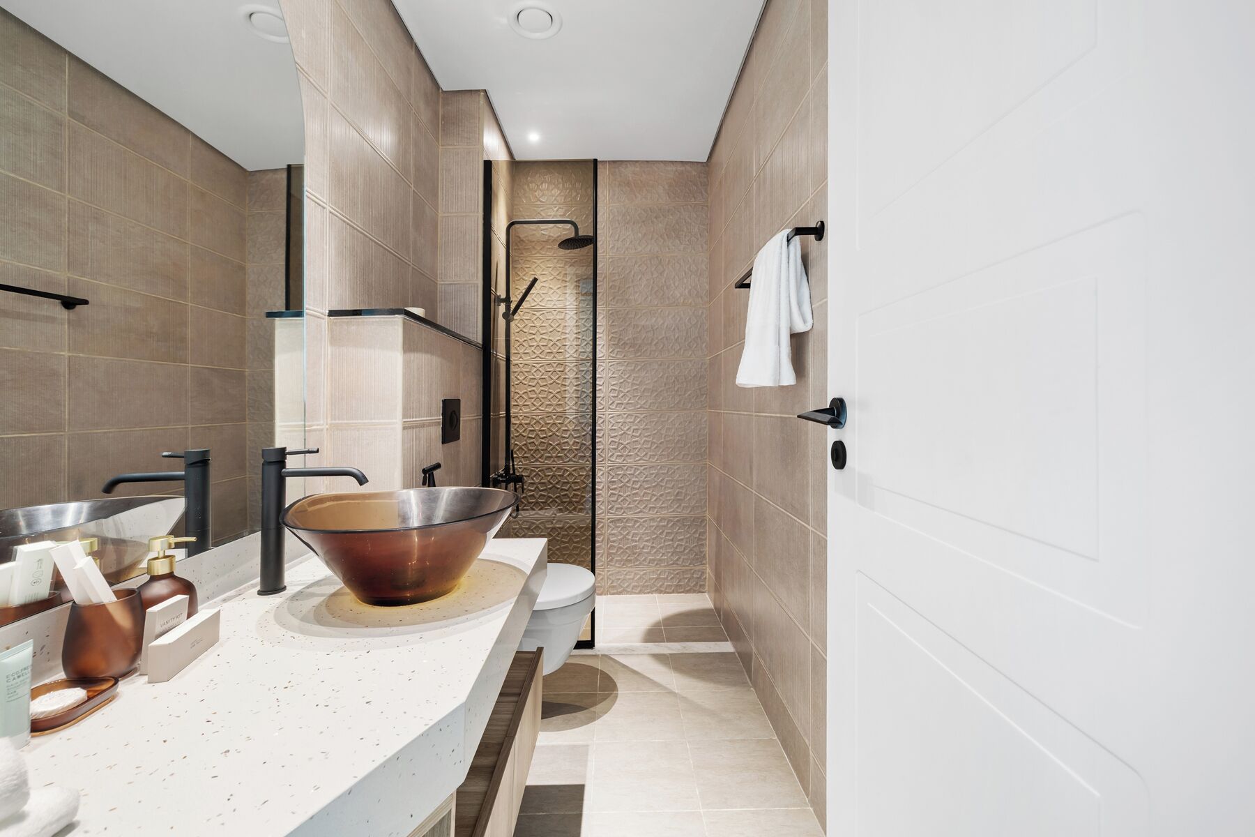 A modern bathroom with a large bowl sink, a shower, and a toilet.