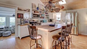 Un'ampia cucina con mobili in legno, un'isola centrale con sgabelli e un lampadario a sospensione.