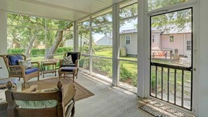 Un portico riparato con mobili in vimini, un tavolo da pranzo e vista su una zona residenziale.