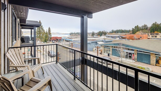 Une terrasse en bois avec des chaises, une vue sur une ville et un bâtiment avec un toit bleu.