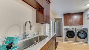 Una cocina con un lavamanos de acero inoxidable, armarios de madera y lavadora y secadora integradas.