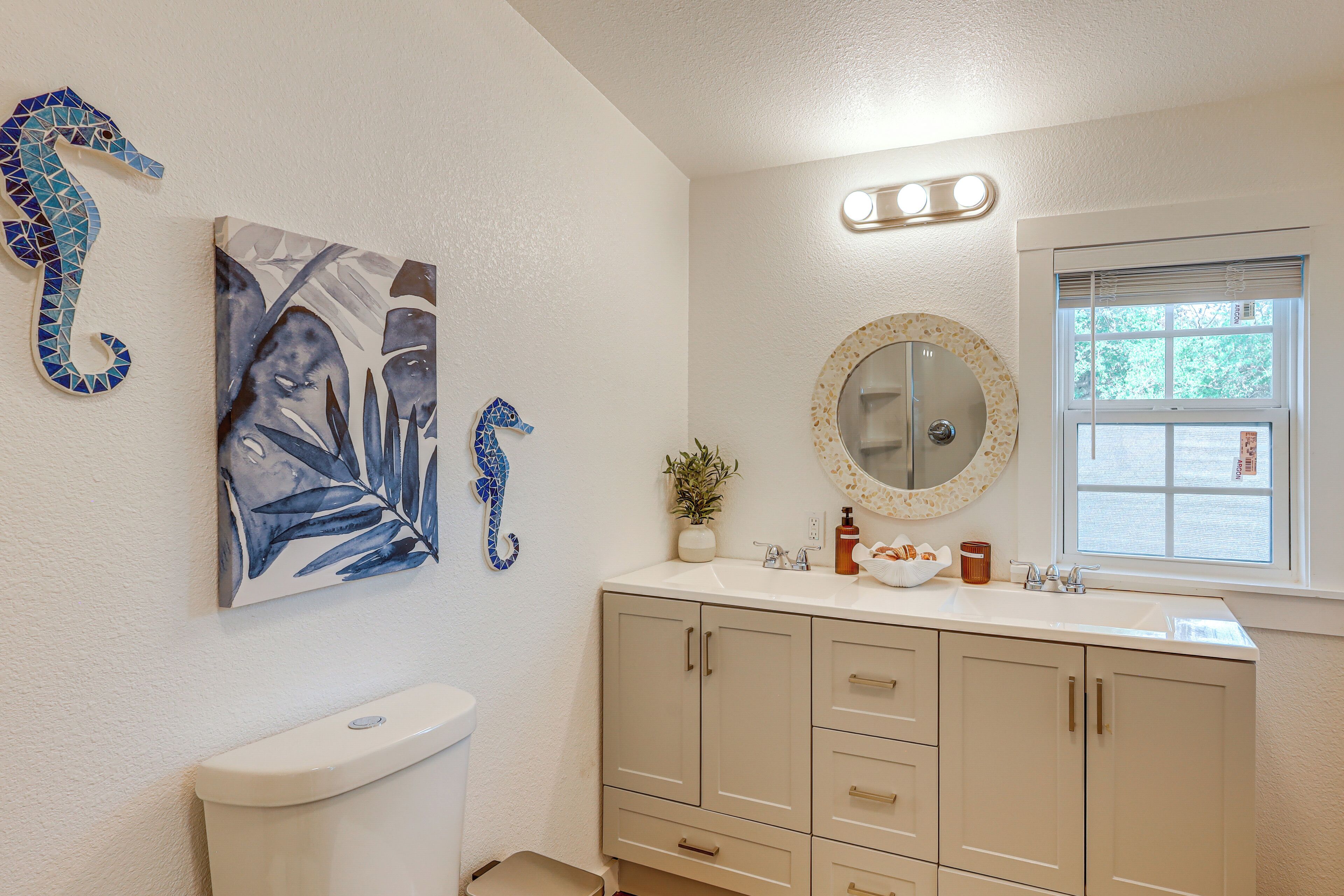 Une salle de bain avec des toilettes, un lavabo avec un miroir et une fenêtre.